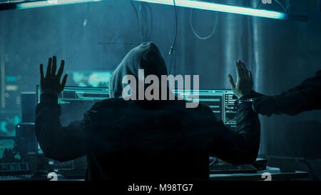 Fully Armed Special Cybersecurity Forces Soldier Arrests and Handcuffs Highly Dangerous Hacker. Hideout is Dark and Full of Computer Equipment. Stock Photo