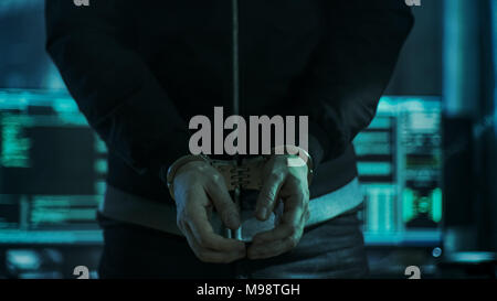 Close-up of Hacker Getting Handcuffed at His Hidden Place by Cybersecurity Police Officer. Stock Photo