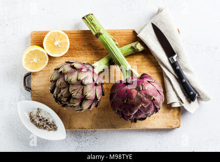 Fresh big Romanesco artichokes green-purple flower heads ready to cook seasonal food Stock Photo