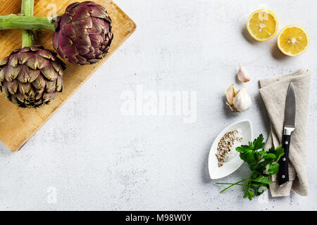 Fresh big Romanesco artichokes green-purple flower heads ready to cook seasonal food. overhead with copy space Stock Photo