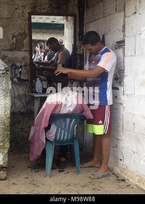 A man getting a haircut outdoors by a street Barber in Caracas. Stock Photo