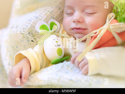 Portrait of a cute little baby boy sleeping in his bed at home with decorated egg-bunny toy, traditional Easter symbol, happy Easter, spring holiday Stock Photo