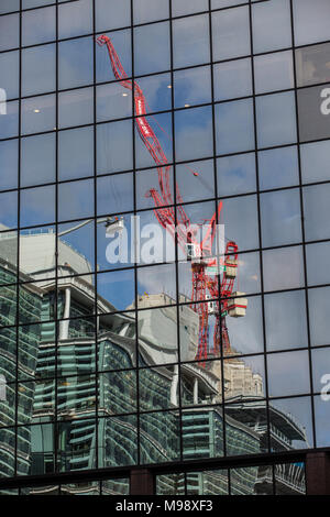 Construction crans on the skyline of Birmingham, West Midlands, UK.  A crane is reflected in the window of an office block. Stock Photo