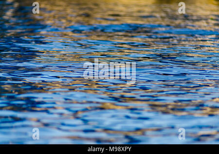 Background image featuring gold and blue ripples on the waters of Lake Maxinkuckee in Culver, Indiana Stock Photo