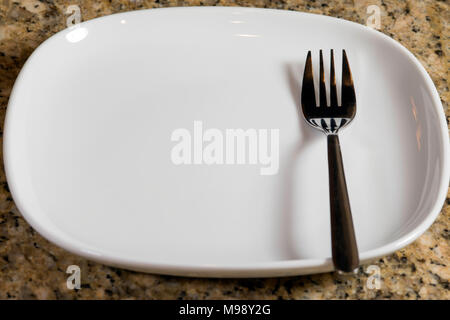 fork on the right side of a square white plate Stock Photo
