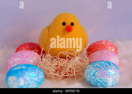 six colorful pastel eggs with a yellow chick sitting in a nest close up. Cloud background on a cloud like white fur on the bottom. Easter photography. Stock Photo