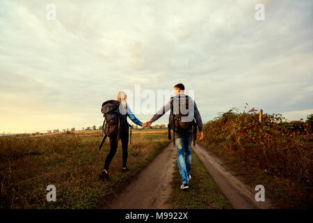 Rear view of tourists walking along the road in nature in the evening. Stock Photo