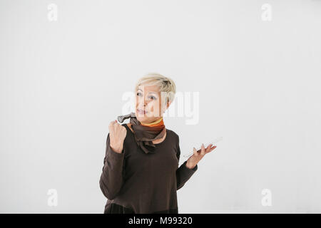 A positive modern elderly woman holds a tablet in her hands and uses it. The gesture shows the word yes, positive and successful. The older generation and modern technology. Stock Photo