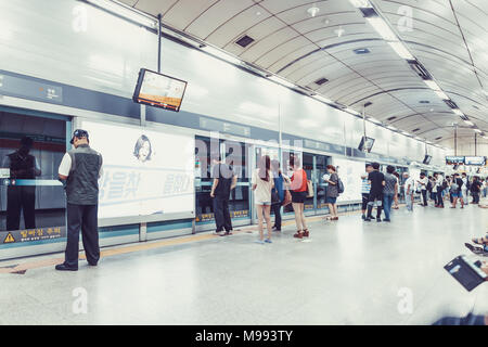 SEOUL, KOREA - AUGUST 12, 2015: Lots of different people standing in the line on a subway platform and patiently waiting for their train to come - Seo Stock Photo