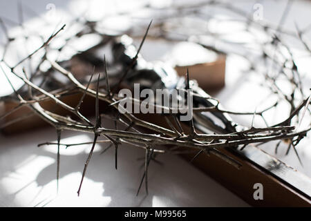 Crown of thorns and crucifix in dramatic lighting. Stock Photo