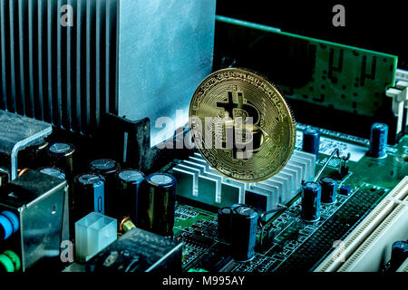 A bitcoin concept with tokens on a computer circuit board showing the currency is virtual Stock Photo