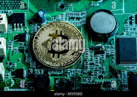 A bitcoin concept with tokens on a computer circuit board showing the currency is virtual Stock Photo