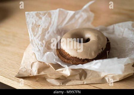 Ready to Eat Gluten-Free Donut on Parchment Paper and Brown Paper Bag Stock Photo