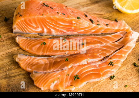 Salmon fillet sashimi fillets raw slices preparing and ready to eat on a wooden rustic cutting board - orange - lemon brown bread Stock Photo