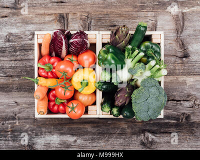 Fresh tasty colorful vegetables in wooden crates on a rustic wooden table Stock Photo