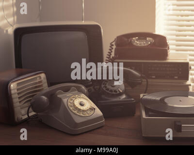 Vintage retro revival objects and second-hand appliances collection on a table: record player, television, radio and rotary dial telephones Stock Photo
