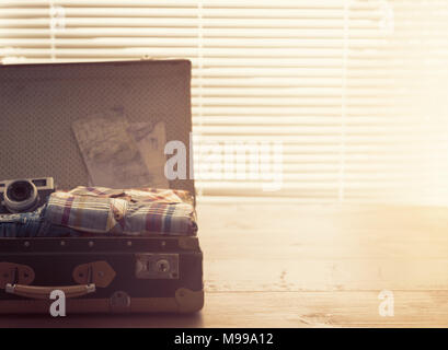 Open vintage suitcase with clothes, camera and maps: retro revival and travel concept Stock Photo