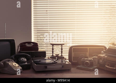Vintage retro revival objects and second-hand appliances collection on a table: record player, television, radio and rotary dial telephones Stock Photo