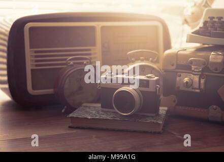 Vintage objects on a desk: suitcase, camera, radio and alarm clocks Stock Photo