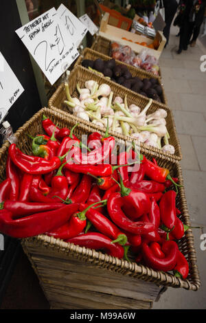 Colourful show of bright red chillies, garlic and avocados on a pavement display outside an independent green grocers shop in the UK Stock Photo