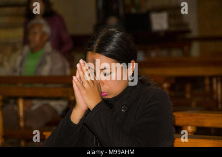 QUITO, ECUADOR, FEBRUARY 22, 2018: Indoor view of unidentified people praying inside of la Catedral church in Quito's Cathedral Stock Photo