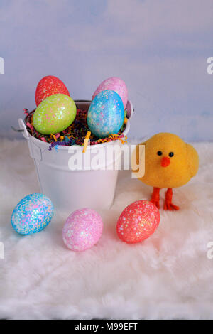white bucket of Easter Eggs in a vertical format with a yellow chick on the side of the bucket with a clouds background Stock Photo