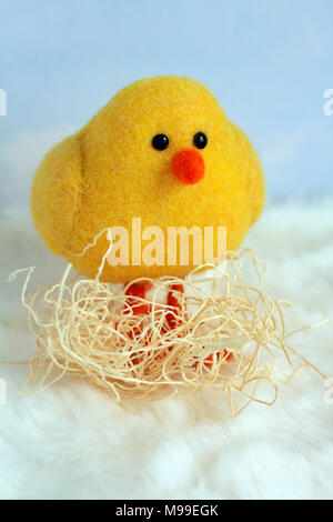 farm animal yellow adorable little baby chick in nest vertical format with nesting material around his legs clouds background and white bottom Stock Photo