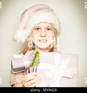Young child girl dressed in Santa Claus hat with Christmas gift Stock Photo
