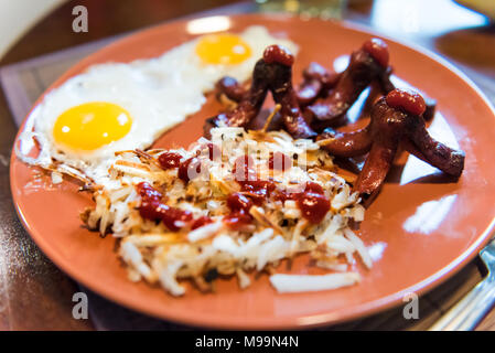 Closeup of large breakfast brunch plate with fried eggs, hash browns shredded potatoes, ketchup, sausage tako octopus Stock Photo