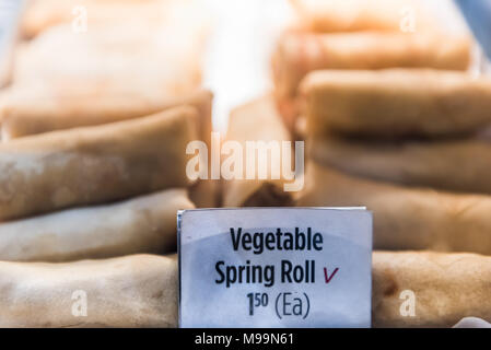 Closeup of fried greasy vegetable spring rolls, sign on tray display in restaurant, fast food, unhealthy chinese cuisine Stock Photo
