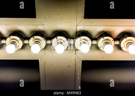 Industrial lamp bulbs up hanging on ceiling in warehouse, grunge old building interior closeup, metal Stock Photo