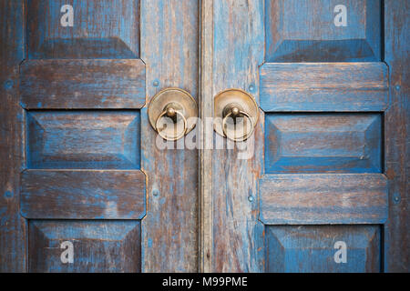 Blue painted aged worn wooden door with metal circle handle Stock Photo