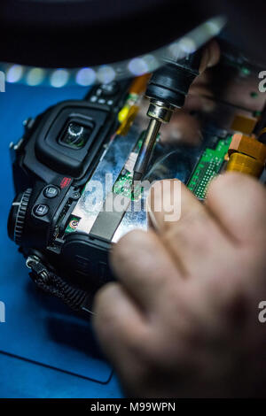 Reparing electronics devices, hands and tools, mobiles and computers. Nikon reparing Stock Photo