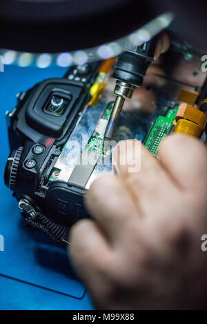 Reparing electronics devices, hands and tools, mobiles and computers. Nikon reparing Stock Photo