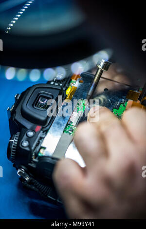 Reparing electronics devices, hands and tools, mobiles and computers. Nikon reparing Stock Photo