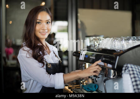 Asian women Barista smiling and using coffee machine in coffee shop counter - Working woman small business owner food and drink cafe concept Stock Photo