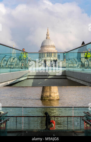 commuters making their way to work across the millenium bridge over the river thames in central london with st pauls saint in the background. landmark Stock Photo