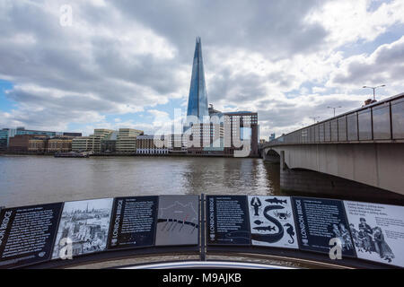 a different or unusual viewpoint or angle of the shard office building in central london. moody atmospheric cloudy skies over london bridge tourists. Stock Photo