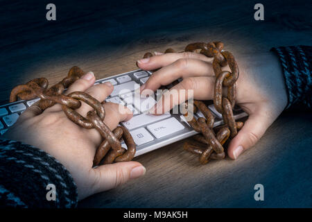 Close-up of hands, keyboard and old rusty chains on dark wood background. Censorship, spy, digitization, cyber security, personal data protection-GDPR. Stock Photo