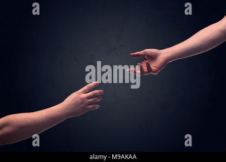 Two male hands reaching out to one another, almost touching, in front of dark clear empty background wall concept Stock Photo