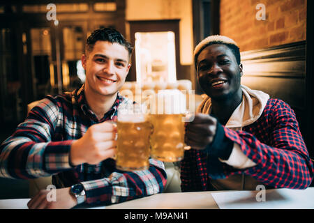 Close up of a two happy male friends drinking beer at pub Stock Photo
