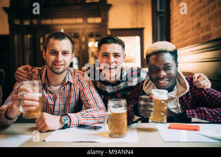 people, men, leisure, friendship and communication concept - happy male friends drinking beer at bar or pub Stock Photo