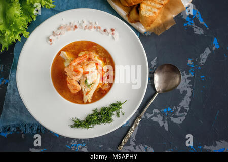 French fish soup Bouillabaisse with seafood, salmon fillet, shrimp, rich flavor, delicious dinner in a white beautiful plate. Close up. Copy spase Stock Photo