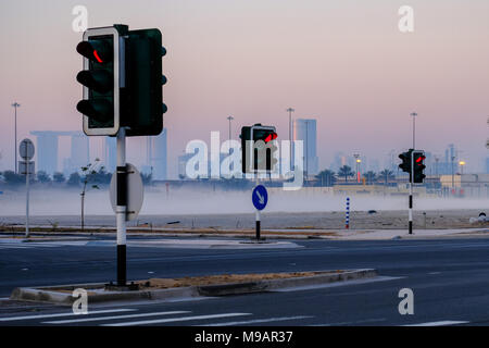 Traffic light posts, captured in a mysty morning with City buildings in a distance, Abu Dhabi, UAE. Stock Photo