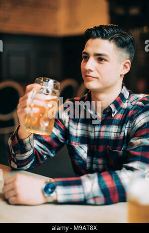 people, drinks, alcohol and leisure concept - man drinking beer from glass at bar or pub Stock Photo