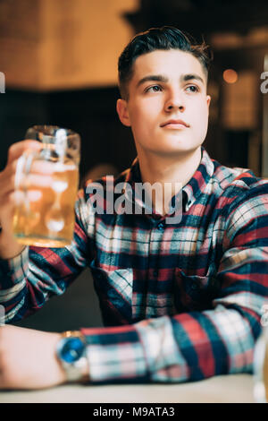 people, drinks, alcohol and leisure concept - man drinking beer from glass at bar or pub Stock Photo