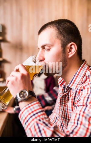 Side view of handsome young man drinking beer while sitting at the bar counter Stock Photo