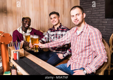 Cheerful old friends having fun and drinking draft beer at bar counter in pub. Stock Photo