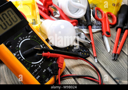 Close-up of a tester and other components for residential electrical installation on rustic wooden table Stock Photo