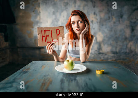 Woman holds help sign against plate with apple Stock Photo
